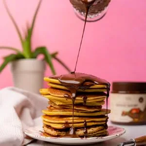 ChocZero Keto Spread Chocolate Hazelnut 12 oz - ChocZero Chocolate Hazelnut Spread drizzled on a stack of pancakes.
