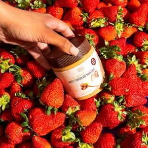 ChocZero Keto Spread Chocolate Hazelnut 12 oz - ChocZero White Chocolate Hazelnut Spread held over strawberries.