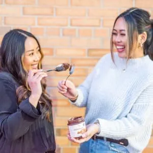 ChocZero Keto Spread Chocolate Hazelnut 12 oz - Two women touching spoons coated in ChocZero Hazelnut Spread
