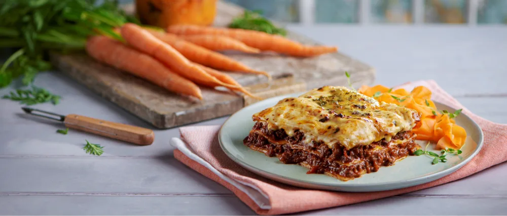 Vegetarian Ready Meals (8 Meals + 3 Sides) Microwavable Long-Life Ready Meal Deal - lasagne on table with carrots in the background