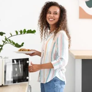 Nutritionally Balanced Ready Meal Variety Box - Parsley Box Microwavable Long-Life Cupboard-Store Ready Meals (7 Meals) - woman microwaving meal