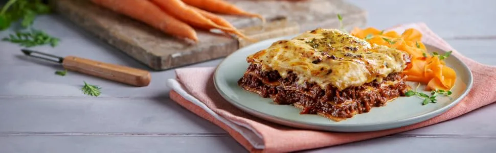 Pasta Microwaveable Ready Meal Deal Selection Pack - Lasagne Macaroni Cheese Bolognese Arrabbiata Penne - lasagne on table with carrots in the background