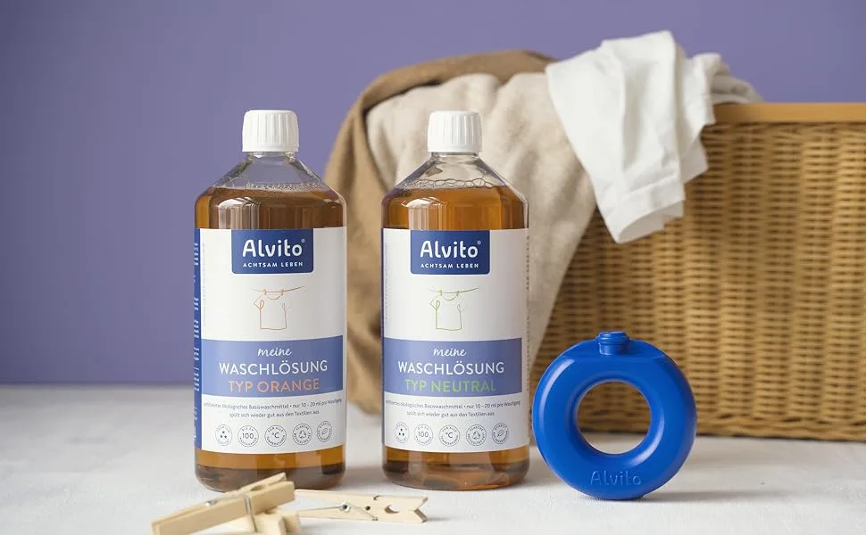 Alvito washing solution type orange ecological detergent concentrate skin-friendly sustainable & vegan dermatologically tested 1l - Zwei Flaschen Waschmittel und ein WaschRing vor einem Korb mit sauberer Wäsche.
