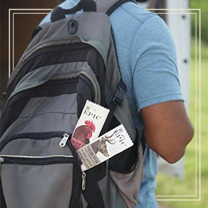 Epic 100% Grass Fed Venison Sea Salt & Pepper Steak Strip 0.8 oz 10 ct - Individual carrying a backpack with two EPIC meat stick snacks