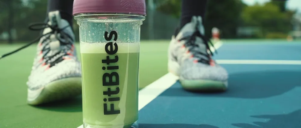 100% Whey Isolate Protein Powder (Matcha Latte) 5.9g BCAAs Gluten Free Zero Sugar Fast Absorbing Easy Digesting Creamy Matcha - FitBites bottle on Tennis Court