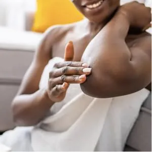 Body Boost Shea Butter Better Balm - smiling black woman in towel rubbing cream on elbow