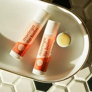 True Moringa Lip Balm - Intense Hydration & Relief for Dry Chapped Lips with Moringa and Shea Butter - 100% vegan paraben free sulfate free ethically sourced - two closed balms and one open one, face up