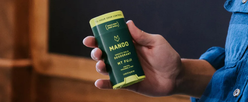 Mando Bourbon Leather Body Deodorant - 72 Hour Odor Control Aluminum Free Baking Soda Free - 3.0 Oz Tube and 2.6 Oz Solid Stick - MANDO Smooth Solid Deodorant in Mt Fuji held in hand