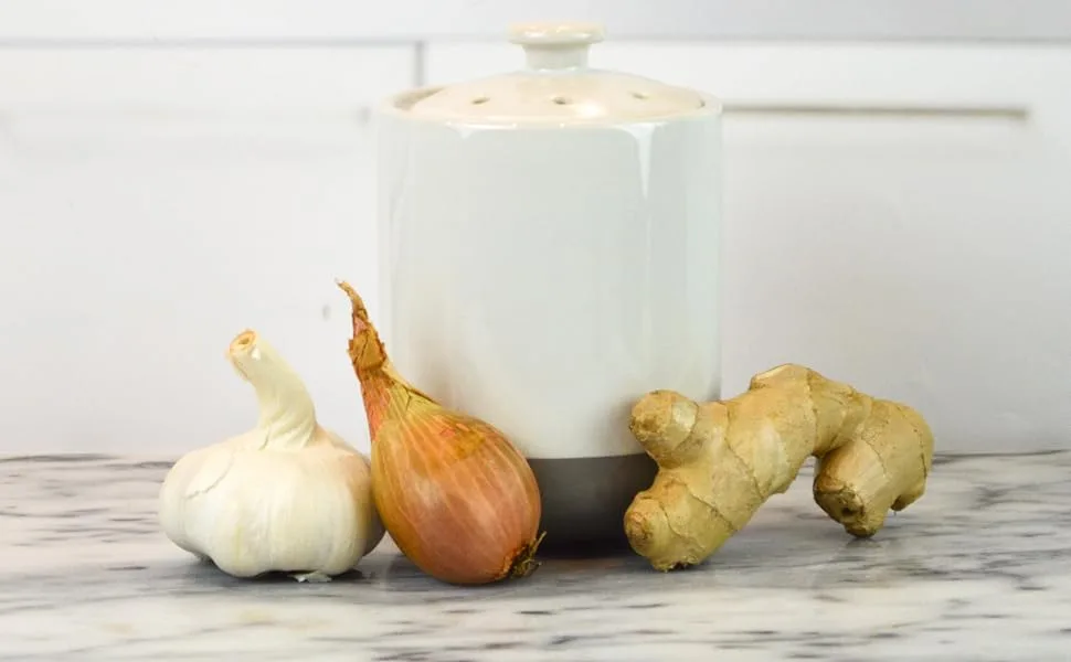 Boston Warehouse Stoneware Garlic Keeper Canister, Grey Reactive Glaze Reactive Glaze Grey - White and Grey Garlic Keeper on a marble kitchen counter with garlic, shallot, ginger