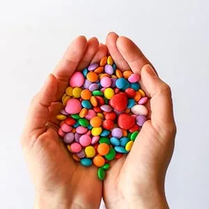 A Great Surprise Halloween Sprinkles - 2.2 LB - Orange, Black, Purple and White Jimmies - hands holding colorful chocolate candy