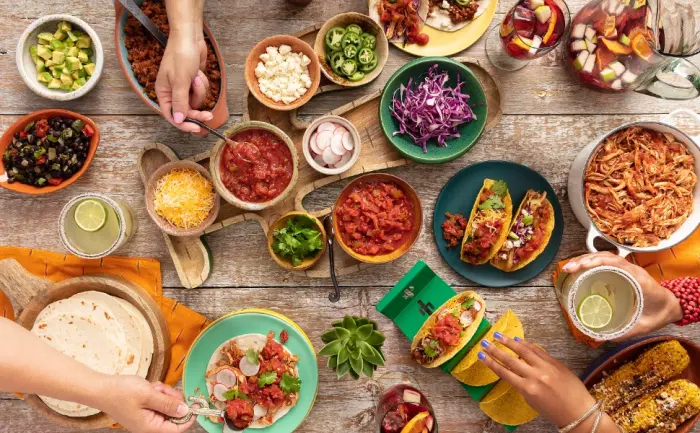 Pace Salsa Con Queso Cheese Dip, Great for Nachos, 15 Ounce Jar (Pack of 6) - Tabletop taco bar with hands serving from dishes of salsa, fresh vegetables and salsa.