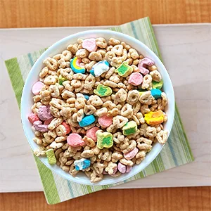 Lucky Charms Marshmallow Clusters Breakfast Cereal, 11.2 OZ - Bowl filled with Lucky Charms gluten free cereal and milk over a table.