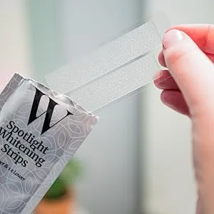 Spotlight Oral Care Teeth Whitening Strips | Gently Whitens Teeth Gradually & Safely (Whitening Strips) 29 Piece Set - Image of hand holding teeth whitening strip