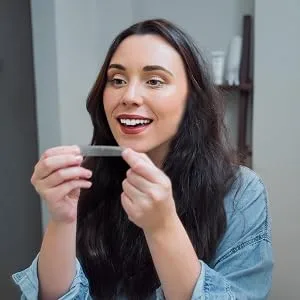 Spotlight Oral Care Teeth Whitening Strips | Gently Whitens Teeth Gradually & Safely (Whitening Strips) 29 Piece Set - Image of woman using teeth whitening strips