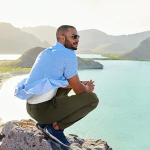 Lands' End School Uniform Kids Active Track Pants 8 Black - A man crouches on some rocks, enjoying the view of a body of water.