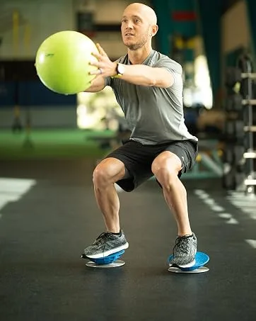 OPTP PRO-Roller Soft Half Foam Roller 36 x 6" x 3 PSFH36B - man balancing on dynamic duos holding an exercise ball in a gym setting