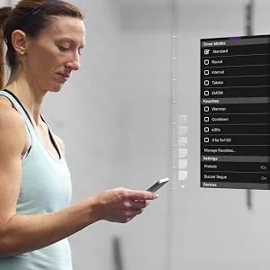 GymNext Flex Timer - Home Edition - Bluetooth App-Controlled LED Interval Timer with Medium 2.3 Digits for Crossfit, Tabata, HIIT, EMOM, MMA, Boxing, Interval Training, Circuit Training, and More - Woman using smartphone to control the Flex Timer using our app
