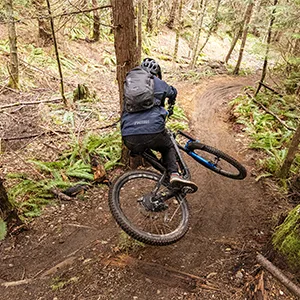CamelBak M.U.L.E. 12 Mountain Biking Hydration Backpack - Easy Refilling Hydration Backpack - Magnetic Tube Trap 100oz Black - Mountain biker wearing MULE Evo bike hydration backpack on a twisting trail.