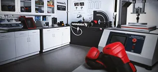 Hayabusa T3 Striking Shinguards Medium Black - Hayabusa Research & Development Lab with a Pair of Red/Black T3 Boxing Gloves on a table