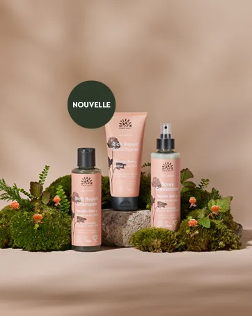 Urtekram Nutricosmetics Coconut Hand Cream Urtekram 75 ml - Le texte se lit comme suit : « NOUVELLE ». Photographie de produit montrant des bouteilles et des contenants de soins de la peau roses disposés de manière artistique avec un feuillage vert sur fond beige neutre.