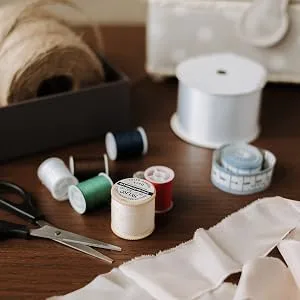 LEONIS 30 Color Handy Polyester Sewing Threads 45 m / 50 yds Each   93011   A.50yd - sewing materials laid out on the table with thread spools in a few colors, scissors, tape measure