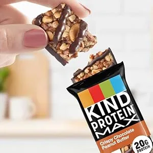 KIND Protein MAX Raspberry Cocoa Crisp 20g Protein 1g Sugar Low Sugar High Protein Snack Bars 4 Count 1 Count (Pack of 4) - A person's hand breaking off a piece of a KIND Protein Max Crispy Chocolate Peanut Butter Bar