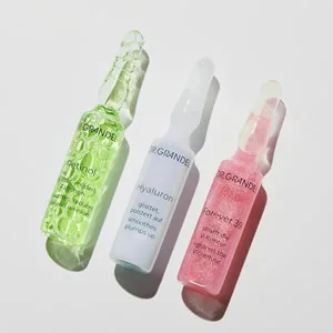 DR. GRANDEL Retinol Ampoules I smoothing, refining, regenerating ampoule against the signs of time - Three glass bottles containing colorful liquids: green, clear, and pink. The bottles have dropper caps and appear to be skincare or beauty products.