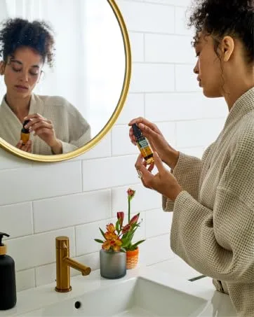 Herb Pharm Daily Immune Builder Herbal Immune System Defense - 4 Ounce 4 Fl Oz (Pack of 1) - Person wearing a robe in a bathroom holding Herb Pharm&amp;#39;s soothing throat spray.