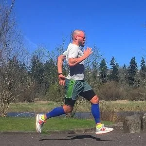 Zensah Thigh Compression Sleeve   Hamstring Support  Quad Compression Sleeve for Men and Women - Thigh Sleeve Wrap  Great for Running  Sports  Groin Pulls Medium Midnight Black - male athlete running in Zensah Compression thigh sleeve in black