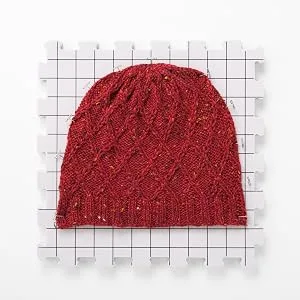 Knit Picks Premium Blocking Mats for Knitting and Crochet Pack of 9 Extra Thick Blocking Boards with Grids Includes 100 T-Pins and Storage Bag - A bright red knit wool hat blocks on one blocking mat