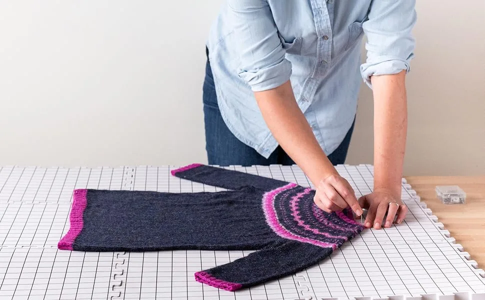 Knit Picks Premium Blocking Mats for Knitting and Crochet Pack of 9 Extra Thick Blocking Boards with Grids Includes 100 T-Pins and Storage Bag - A person uses the blocking mats and pins to block a knit sweater