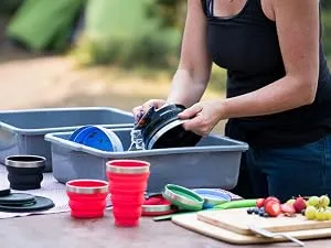HYDAWAY Collapsible Bowl Set | 2-Pack | Glacier Blue - A woman doing camp dishes with HYDAWAY Collapsible bowls, pints and cups