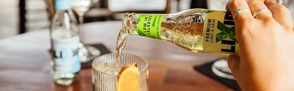 Lixir Premium Soda Water Premium Mixer 24 x 200ml Recyclable Glass Bottles - lixir ginger ale being poored into a glass on a wooden table